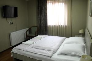 een slaapkamer met een bed met witte lakens en een raam bij Apartment Erekle 6 in Borjomi