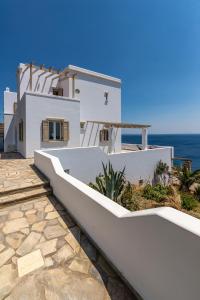 een wit huis met de oceaan op de achtergrond bij La Chapelle Ouest & Guest suite in Agios Romanos