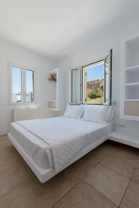 een groot wit bed in een witte kamer met ramen bij La Chapelle Ouest & Guest suite in Agios Romanos