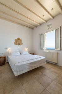 een witte slaapkamer met een groot bed en een raam bij La Chapelle Ouest & Guest suite in Agios Romanos