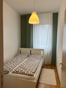 een slaapkamer met een bed, een lamp en een raam bij Sleep-Enjoy Apartment in Novi Sad