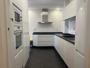 a kitchen with white cabinets and a stove top oven at Piso y parking Zapillo playa in Almería