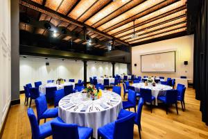a conference room with tables and blue chairs and a screen at Hotel Ferreus Modern Art Deco in Krakow +37 photos