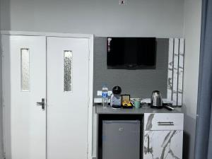 a kitchen with white cabinets and a tv on the wall at Downtown Inn Madaba in Madaba