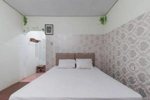 a bedroom with a large bed with white sheets at Hotel Linggarjati near Natural Park TWA Linggarjati in Bojong