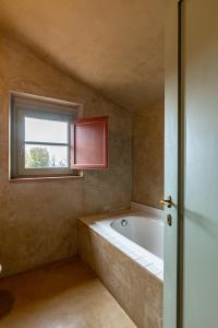 baño con bañera y ventana en Le Ragnaie, en Montalcino