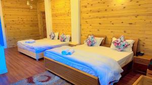 2 łóżka w pokoju z drewnianymi ścianami w obiekcie The Golden Peak, Hotel w mieście Mukteshwar