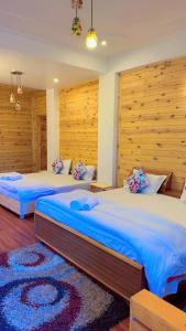 two beds in a bedroom with wooden walls at The Golden Peak, Hotel in Mukteswar