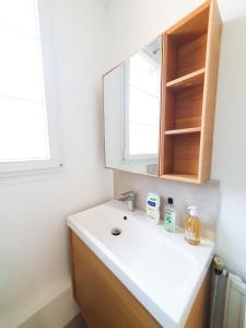 ein Badezimmer mit einem weißen Waschbecken und einem Spiegel in der Unterkunft EXIGEHOME-Appart très lumineux aux portes de Paris in Suresnes