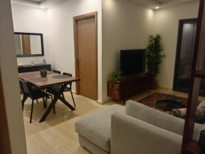 ein Wohnzimmer mit einem Tisch, einem Sofa und einem TV in der Unterkunft Appartement Parc Mohammedia in Mohammedia