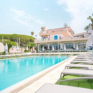 a swimming pool with lounge chairs in front of a building at Le Saline Beach Resort in Saline Joniche