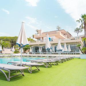 a row of lounge chairs with umbrellas next to a swimming pool at Le Saline Beach Resort in Saline Joniche