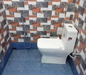 een badkamer met een toilet en een tegelwand bij Nidhivan Residency in Navadwīp
