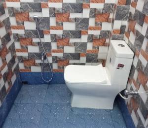 a bathroom with a toilet and a tile wall at Nidhivan Residency in Navadwīp