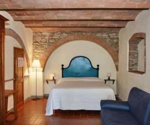 sypialnia z łóżkiem i kanapą w pokoju w obiekcie B&B Countryhouse Villa Baciolo w mieście San Gimignano