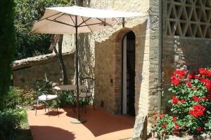 un patio con sombrilla, sillas y flores en B&B Countryhouse Villa Baciolo, en San Gimignano