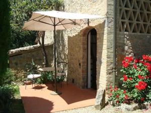 eine Terrasse mit einem Sonnenschirm, Stühlen und Blumen in der Unterkunft B&B Countryhouse Villa Baciolo in San Gimignano