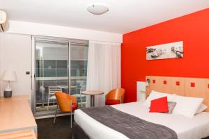 une chambre d'hôtel avec un lit et un mur rouge dans l'établissement Kyriad Prestige Les Sables d'Olonne - Plage - Centre des Congrès, à Les Sables-dʼOlonne