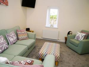 - un salon avec un canapé vert et 2 chaises dans l'établissement Craigielea Cottage, à Newton Stewart