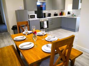- une table en bois avec des verres à vin et des assiettes dans la cuisine dans l'établissement Craigielea Cottage, à Newton Stewart