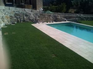 a swimming pool in a yard next to a stone wall at Caramulo - Casas do Espigueiro in Macieira de Alcoba