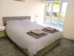 - une chambre avec un grand lit et des serviettes dans l'établissement Craigielea Cottage, à Newton Stewart