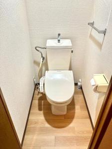 La salle de bains est pourvue de toilettes blanches et de parquet. dans l'établissement Shinjuku Hana House 4mins to Ōkubo Station, à Tokyo