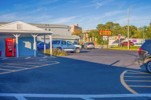 ein Parkplatz mit einer roten Telefonzelle und einer Tankstelle in der Unterkunft Sunrise Inn by OYO Titusville FL in Titusville