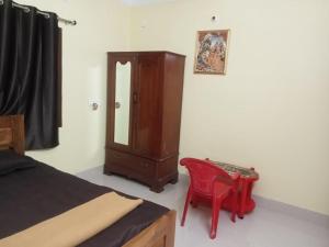 a bedroom with a wooden cabinet and a red chair at Nidhivan Residency in Navadwīp