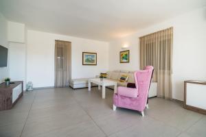 uma sala de estar com uma cadeira rosa e uma mesa em Villa Flavia and Alba - Private Heated Pool em Novalja