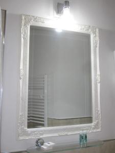 a mirror on a wall above a bathroom sink at B&B Parva Domus in Lamezia Terme