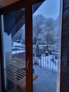 una puerta corredera de cristal que da a un balcón con nieve en el suelo en Gemütliche Wohnung am Waldrand, en Thierhaupten