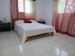 1 dormitorio con cama blanca y cortinas rojas en Maison rénovée à Itaosy Cité Akany Sambatra, en Antananarivo