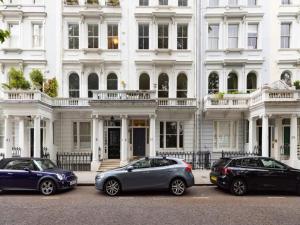 três carros estacionados em frente a um edifício branco em Pass the Keys Spacious and central 2 bedroom flat in Chelsea em Londres