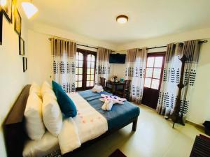 ein Schlafzimmer mit einem Bett mit zwei ausgestopften Tieren darauf in der Unterkunft Thilina Hotel in Nuwara Eliya