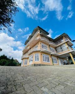 a large building with white windows and a blue sky at Thilina Hotel in Nuwara Eliya