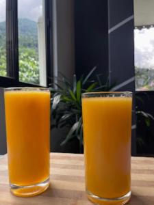 deux verres de jus d'orange assis sur une table dans l'établissement Ashraya Boutique Homestay , Rongli, à Rongli