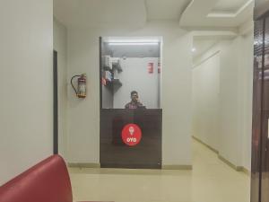um homem num espelho numa sala com uma cadeira vermelha em Hotel Palace Inn Near Don Bosco -Borivali- Metro Station em Mumbai