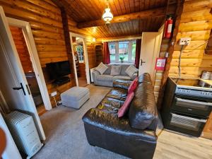 a living room with a leather couch in a cabin at Cosy 2 bedroom Log Cabin in Snowdonia Cabin151 in Trawsfynydd