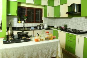 a kitchen with green cabinets and a table with food on it at Jasmin Villa in Cochin