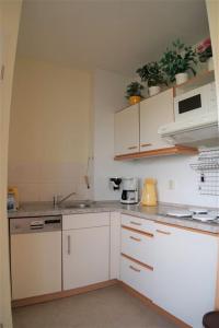 uma cozinha com armários brancos e electrodomésticos brancos em Ferienpark - Haus G, App 0G0308 em Heiligenhafen