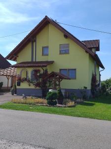 una casa amarilla con flores delante en Ferienwohnung 'am Bienwald', en Schaidt