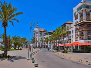 a street in a city with palm trees and buildings at AGADIR MARINA - BEACHFRONT APARTMENT in Agadir