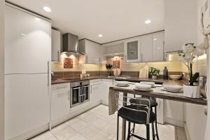 a kitchen with white appliances and a counter with chairs at Hububb Luxury Apartment Kensington in London