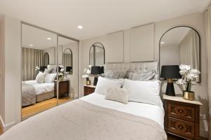 a bedroom with a large white bed and two mirrors at Hububb Luxury Apartment Kensington in London