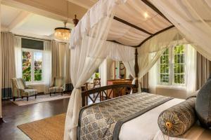 ein Schlafzimmer mit einem Himmelbett und Fenstern in der Unterkunft Castle Hill Bungalow in Kandy