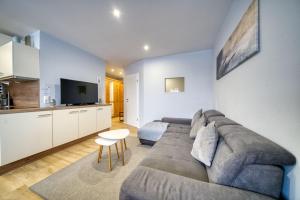 uma sala de estar com um sofá cinzento e uma cozinha em Ferienpark - Haus H, App 0H0404 em Heiligenhafen