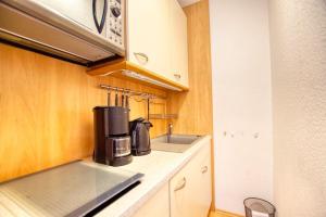 eine kleine Küche mit einer Spüle und einer Mikrowelle in der Unterkunft Ferienpark - Haus G, App 0G1003 in Heiligenhafen