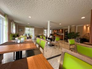 a dining room with tables and green chairs at ROTHSEE Hotel in Allersberg