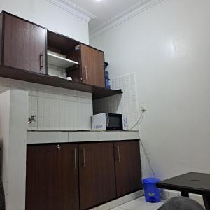 a kitchen with wooden cabinets and a microwave on the counter at Dolphin-holiday homes mombasa in Ndome